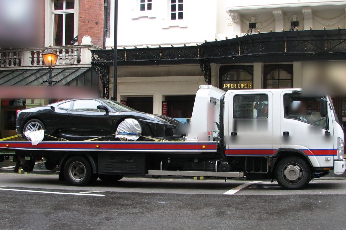 Sports car strapped onto a white UK recovery truck for delivery