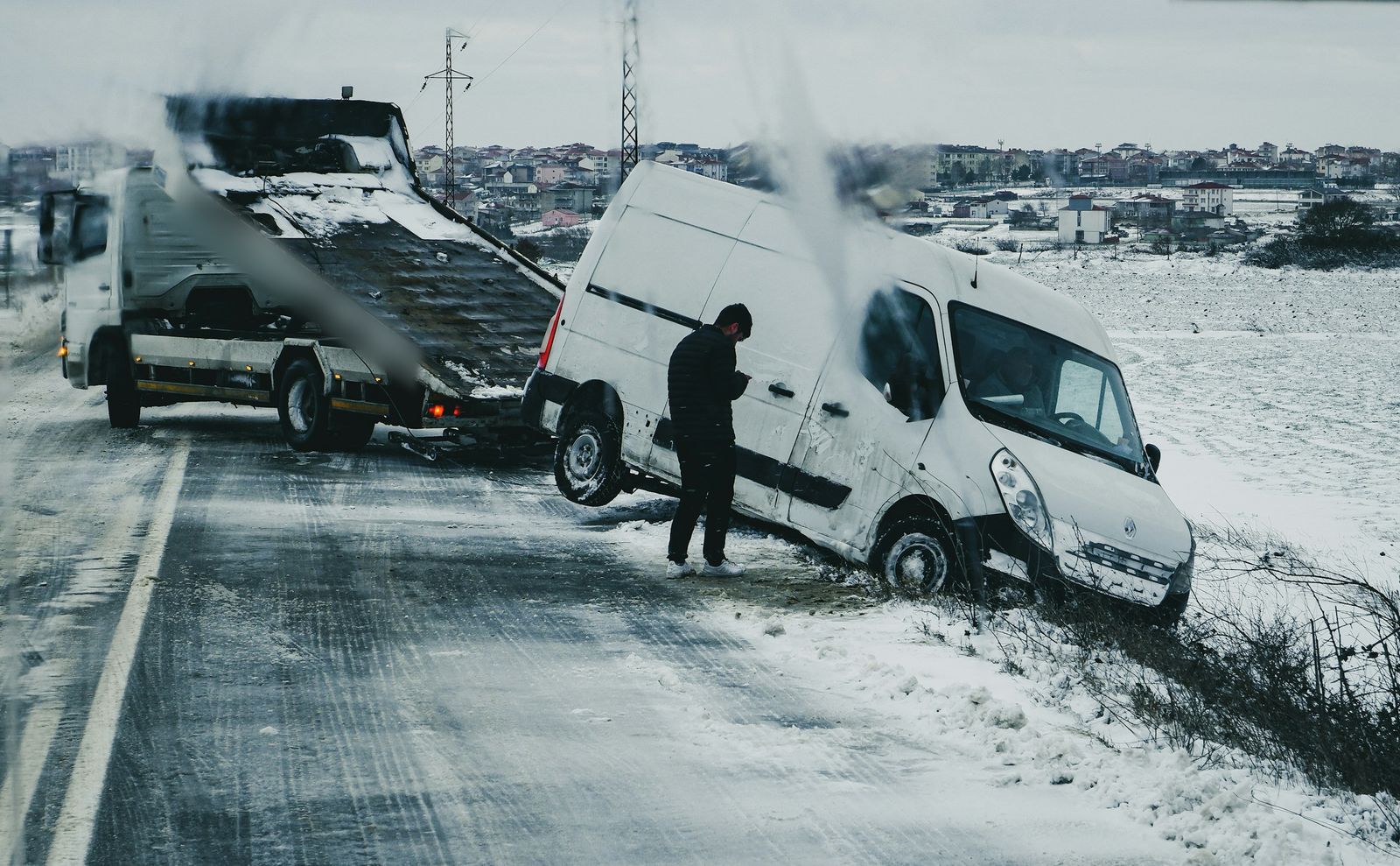 Van being recovered from a snowy roadside ditch onto a recovery truck